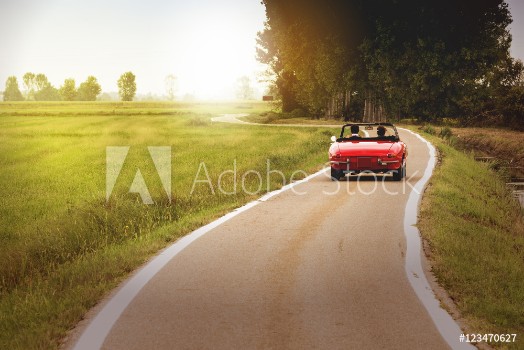 Picture of Classic red convertible car traveling in the countryside at sunset